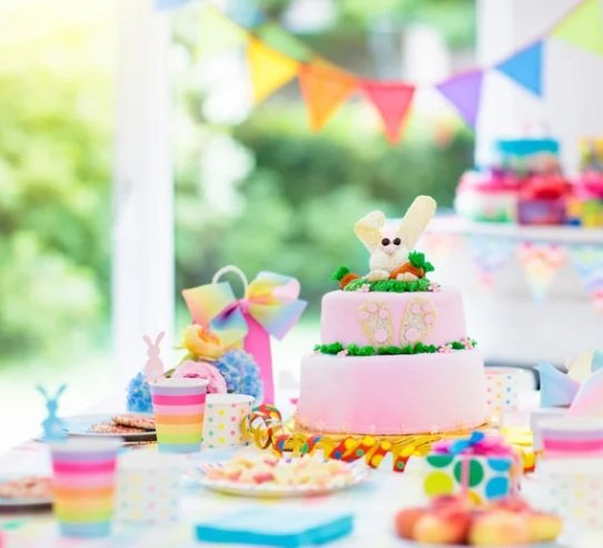 Rainbow coloured party table with cake, cups and decorations